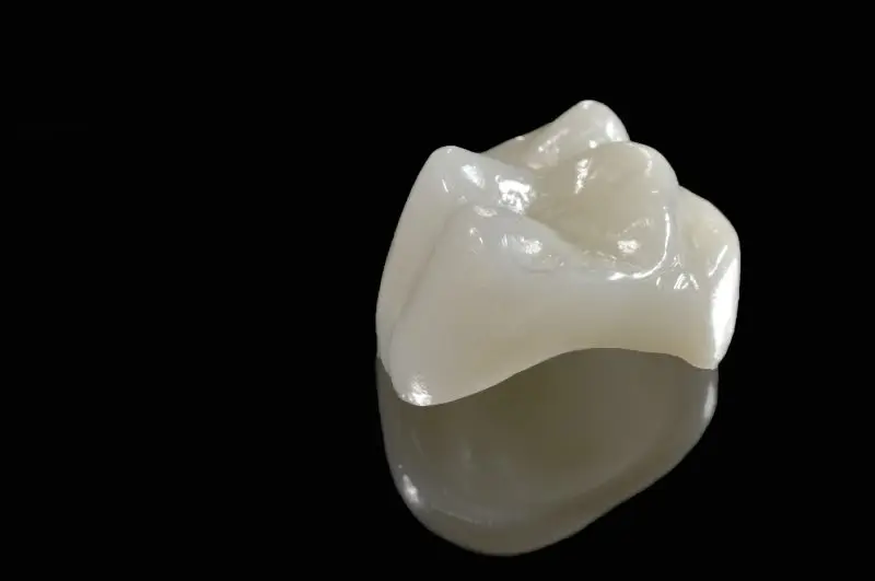 Close-up of a tooth-colored porcelain dental crown on a black background